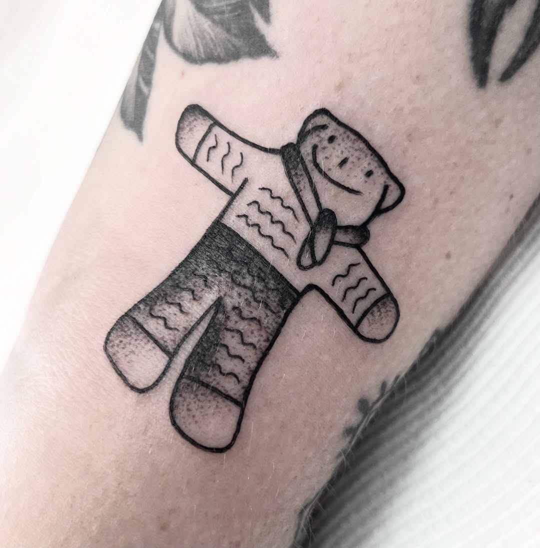 Whimsical teddy bear plush tattoo with bold outlines.
