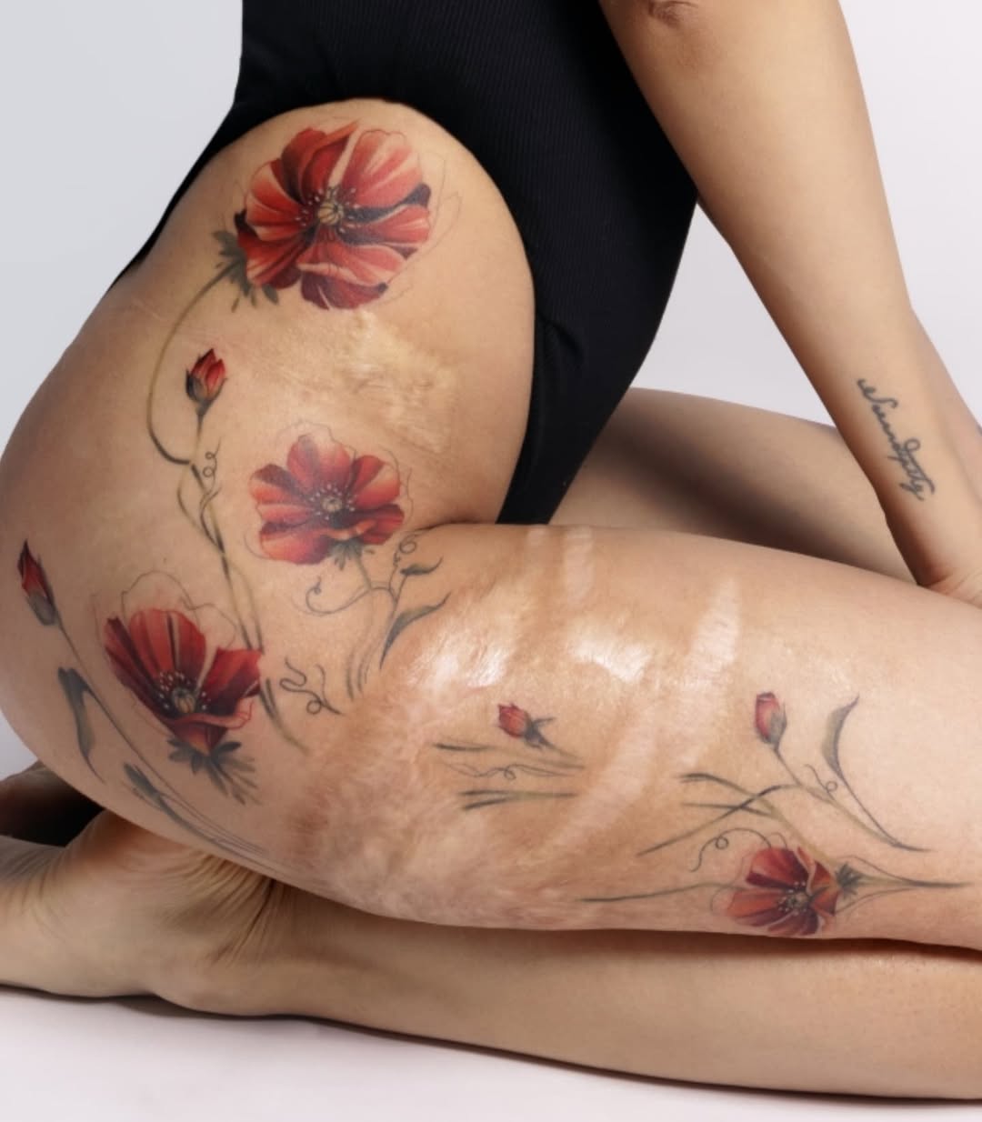 Vibrant red poppies in watercolor on the outer thigh