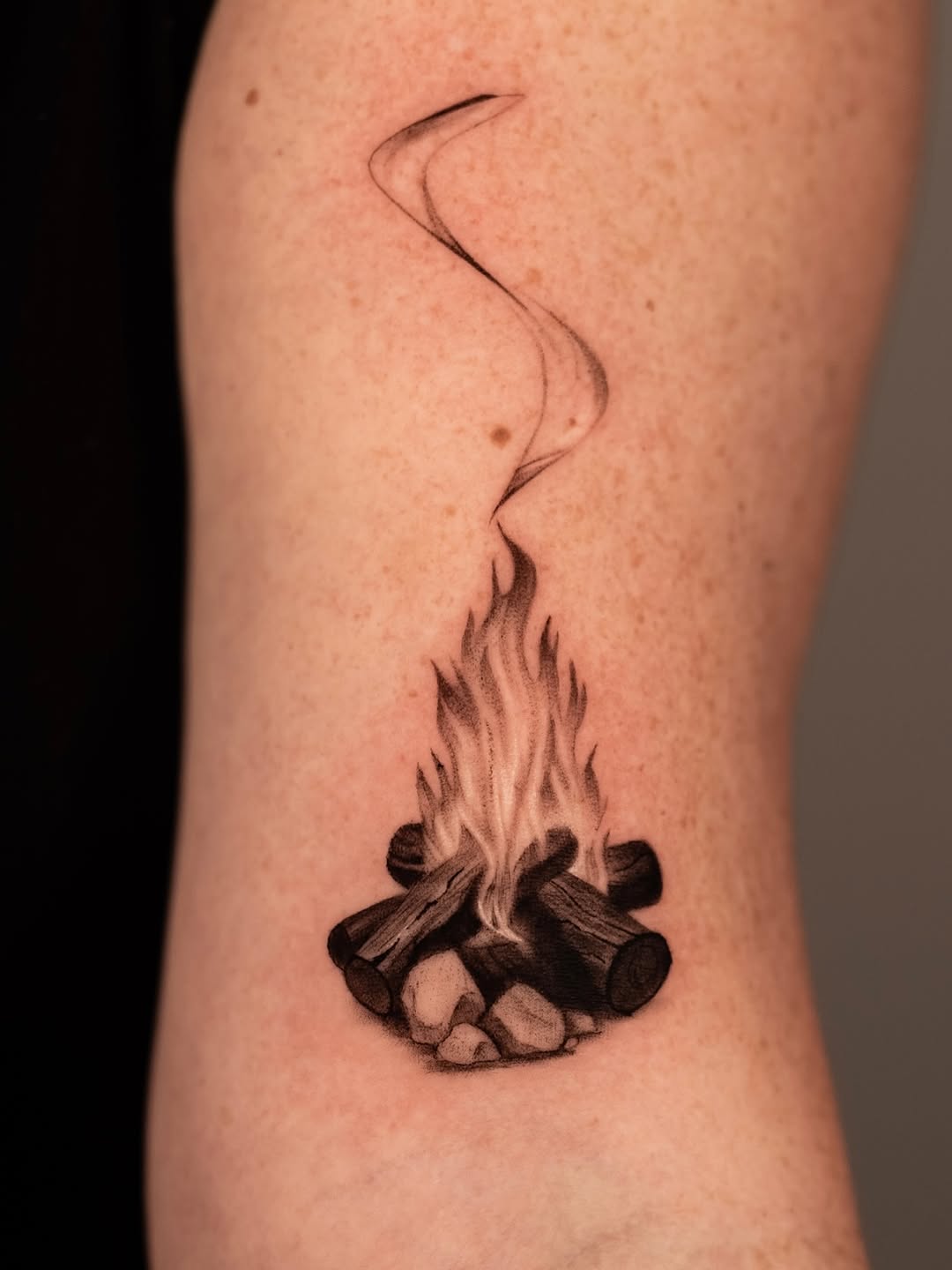 Campfire and rocks in bold blackwork with curling smoke