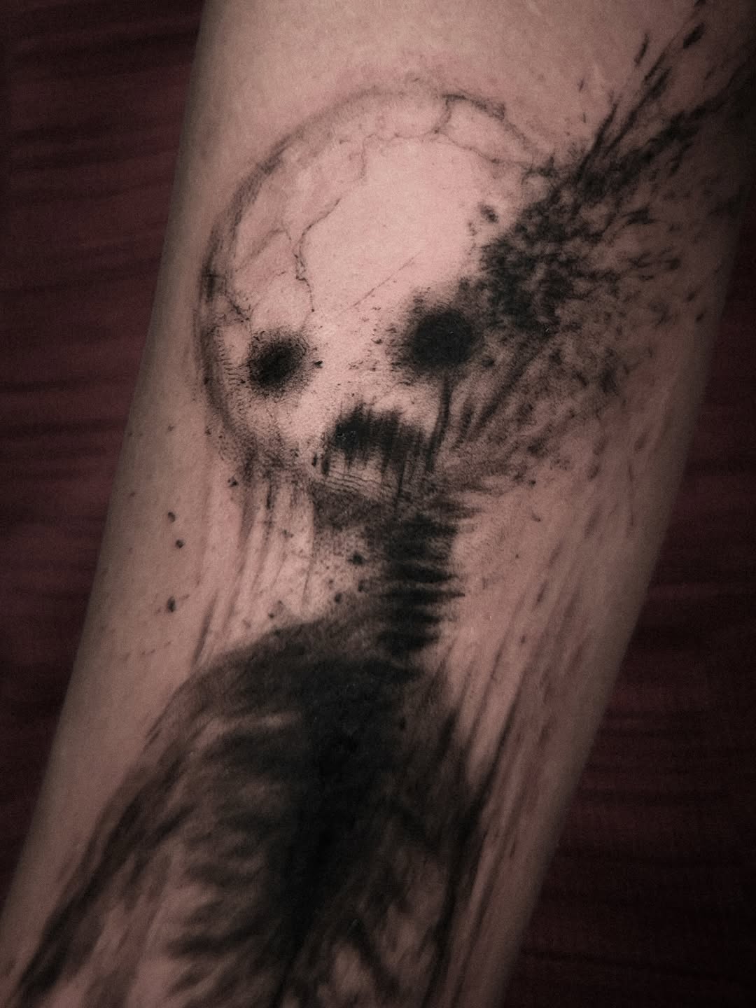 Cracked circular moon motif with bold ink-splatter accents on forearm