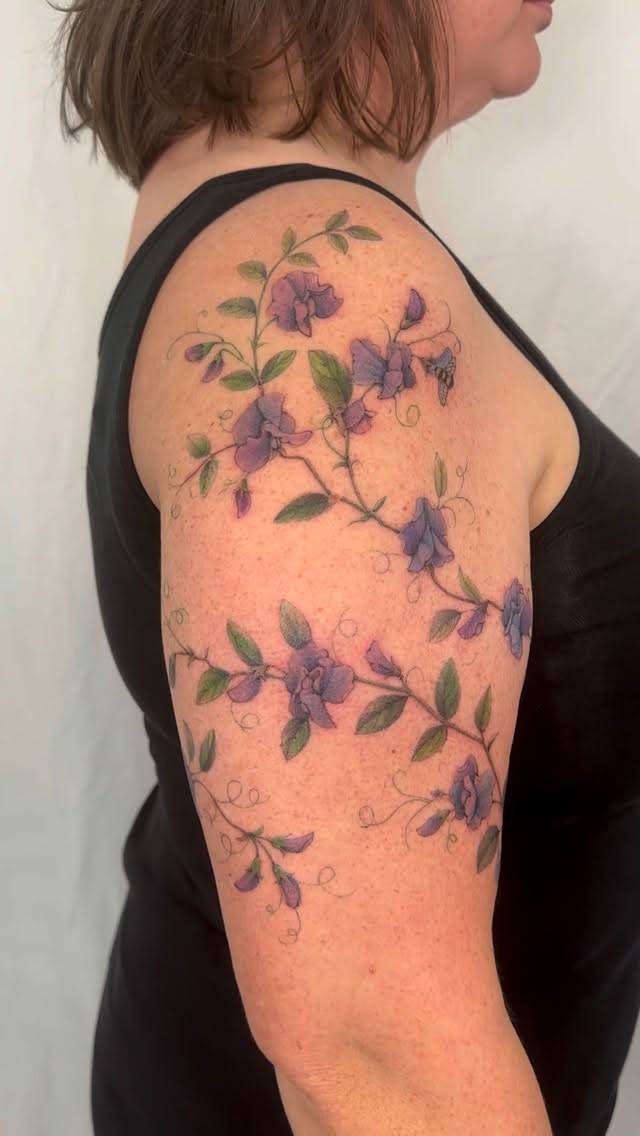 Delicate purple sweet pea vines wrap softly around arm