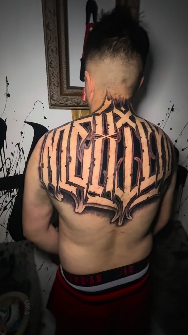 Bold blackwork back piece with jagged, Gothic lettering