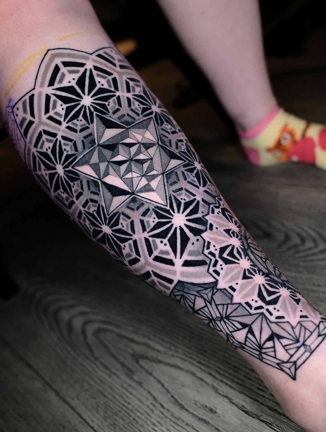 Intricate grayscale geometric leg piece with mandala-inspired motifs