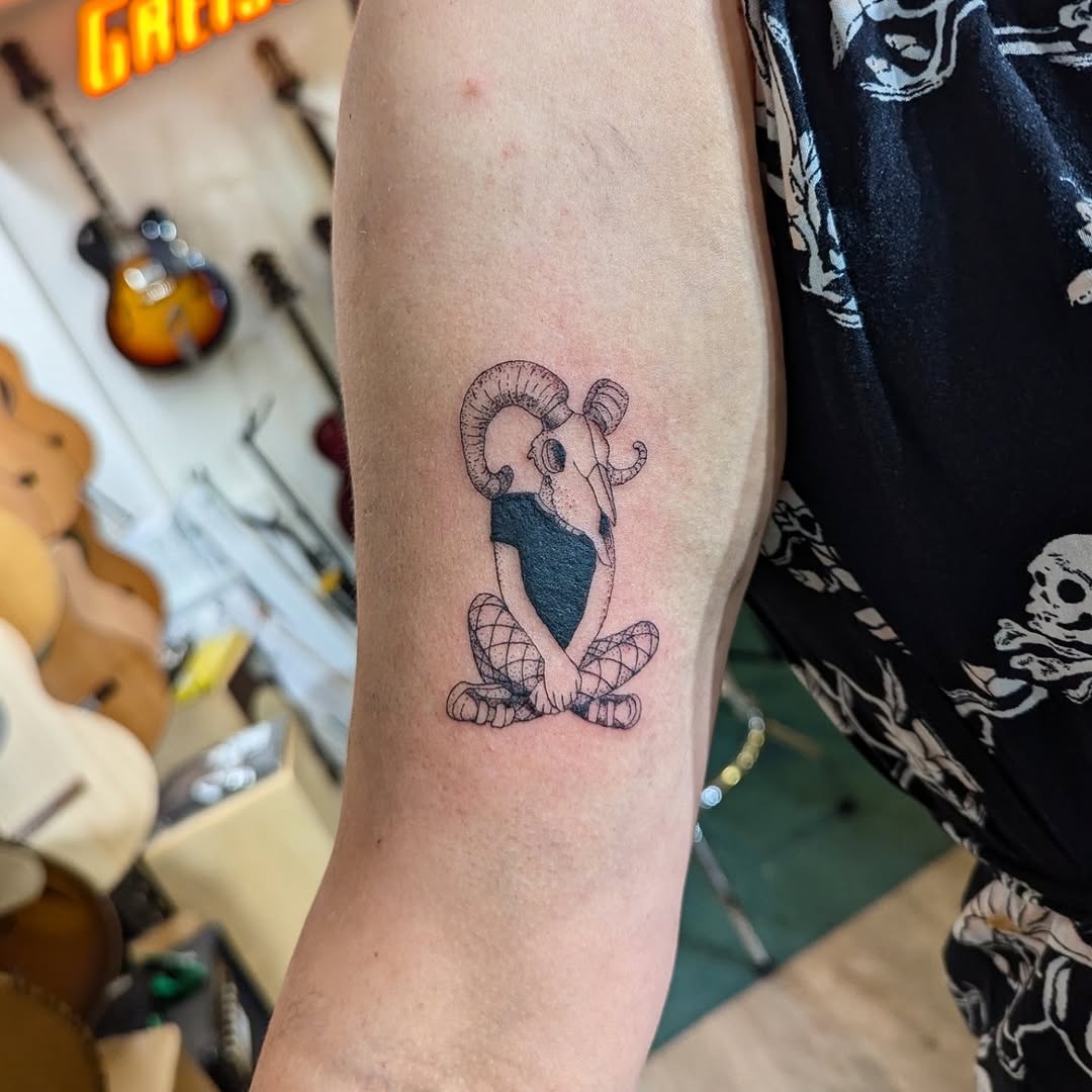 Fine-line ram skull with curled horns, seated.