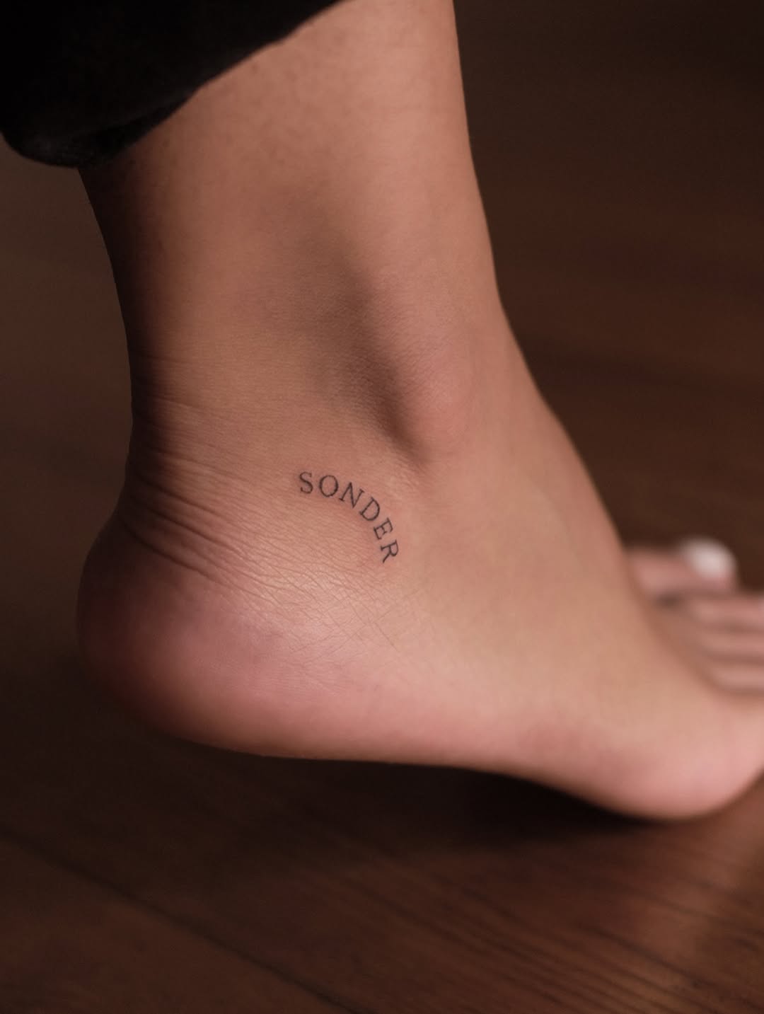 Delicate curved ankle script reading 'Sonder'.