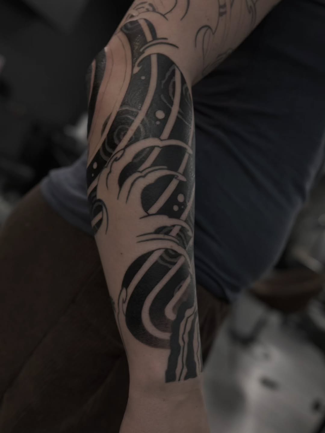 Bold blackwork water-themed forearm sleeve with swirling waves