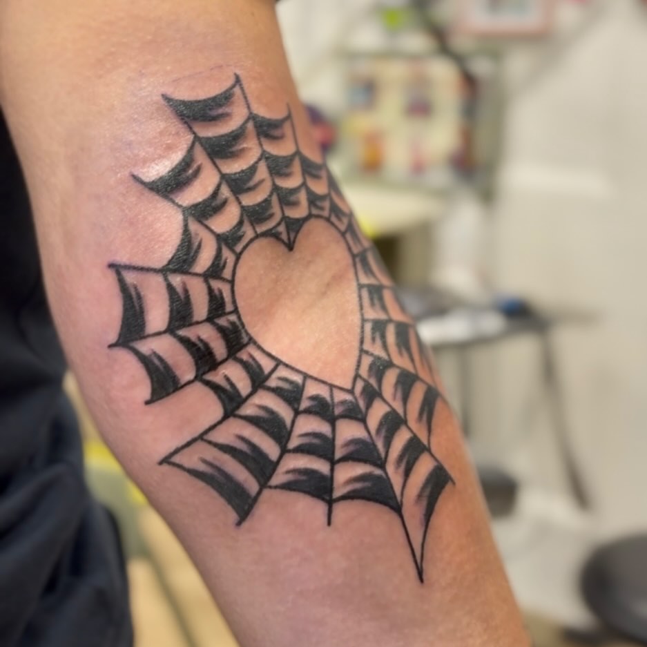 Bold black spiderweb heart on elbow, crisp linework