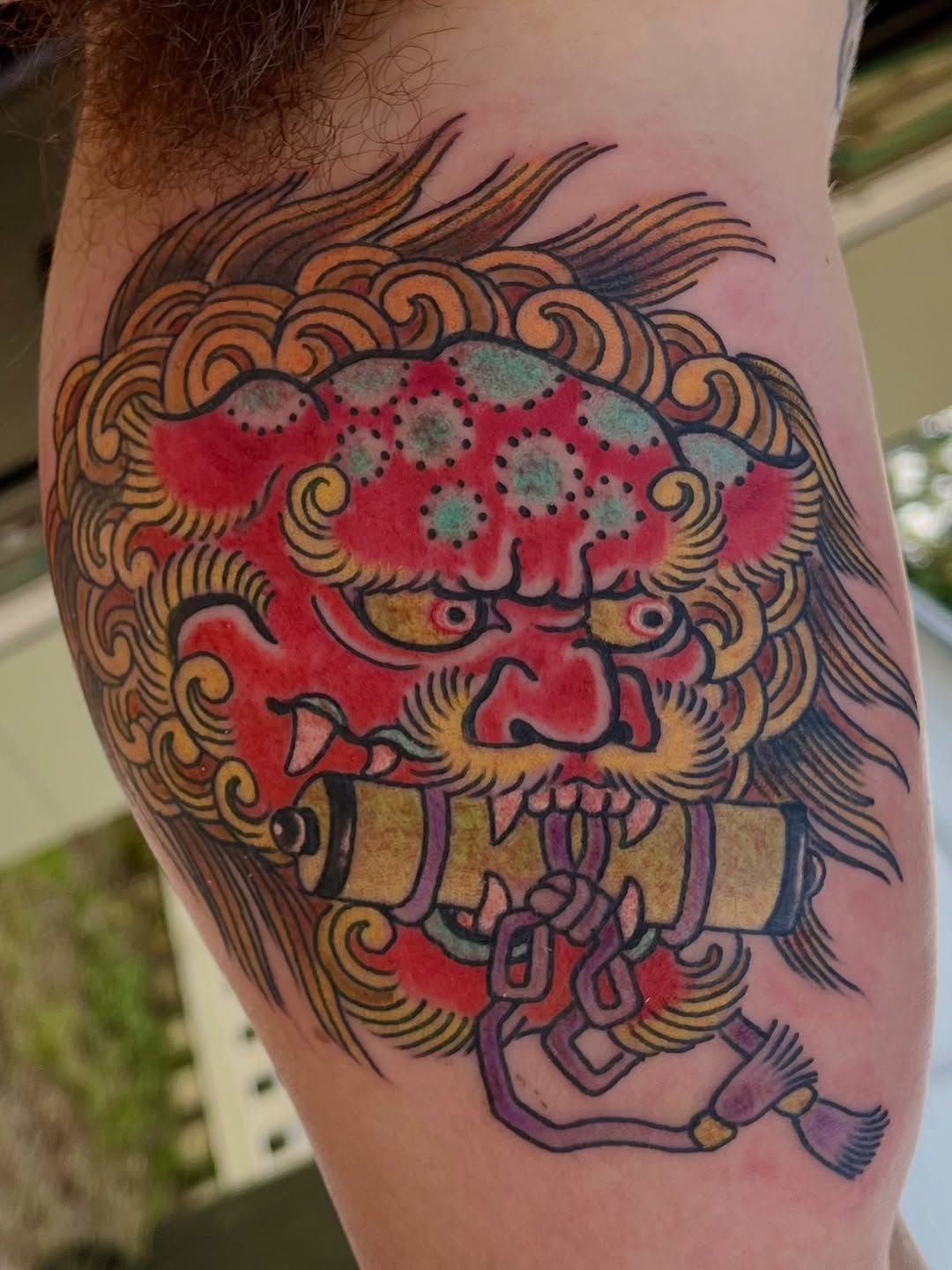 Bold neo-traditional shishi head with red shading and flowing orange mane