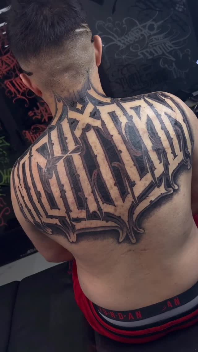 Bold blackletter back piece with dramatic, intricate strokes