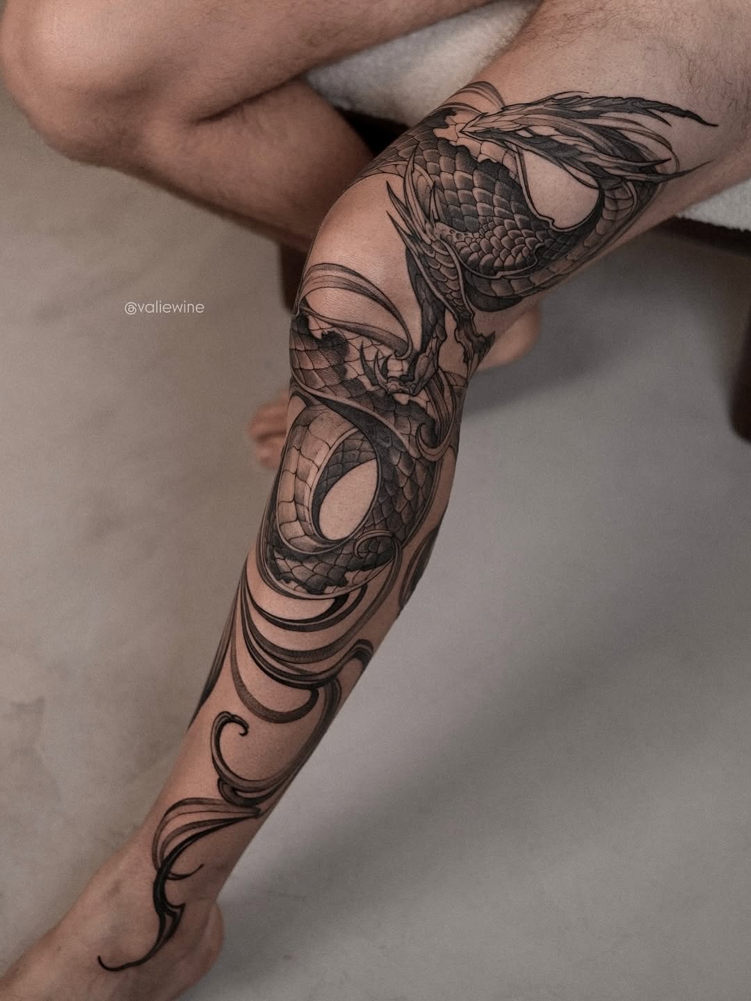 Intricate black-and-gray dragon coils around the forearm.