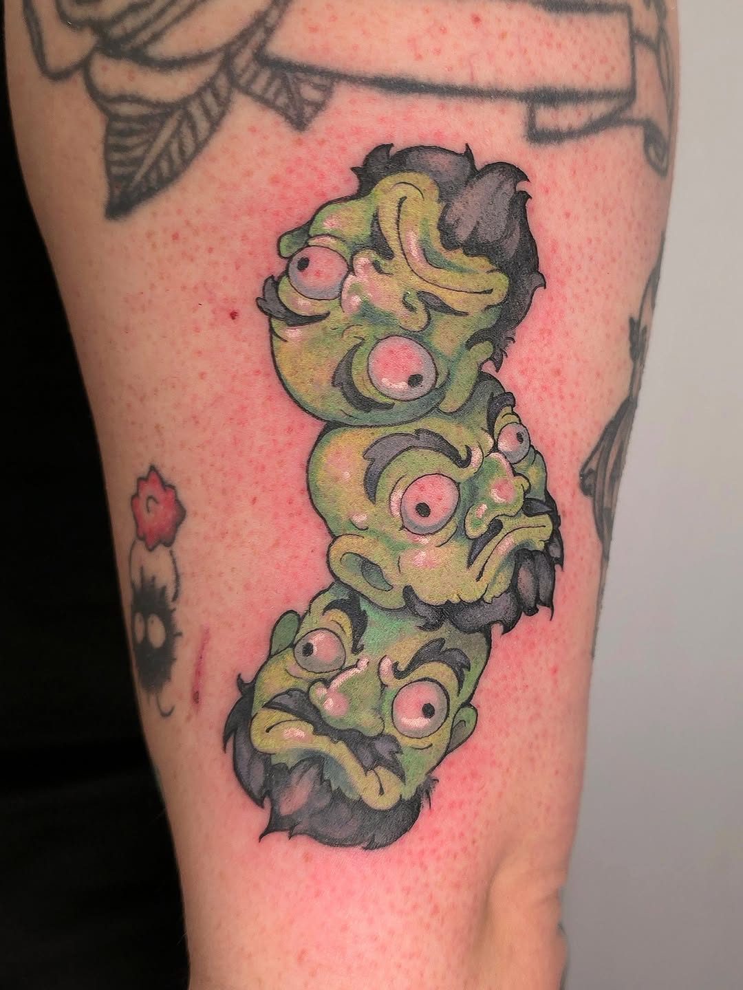 Three grotesque goblin heads stacked, neon-green skin, pink-eyed, bold linework.