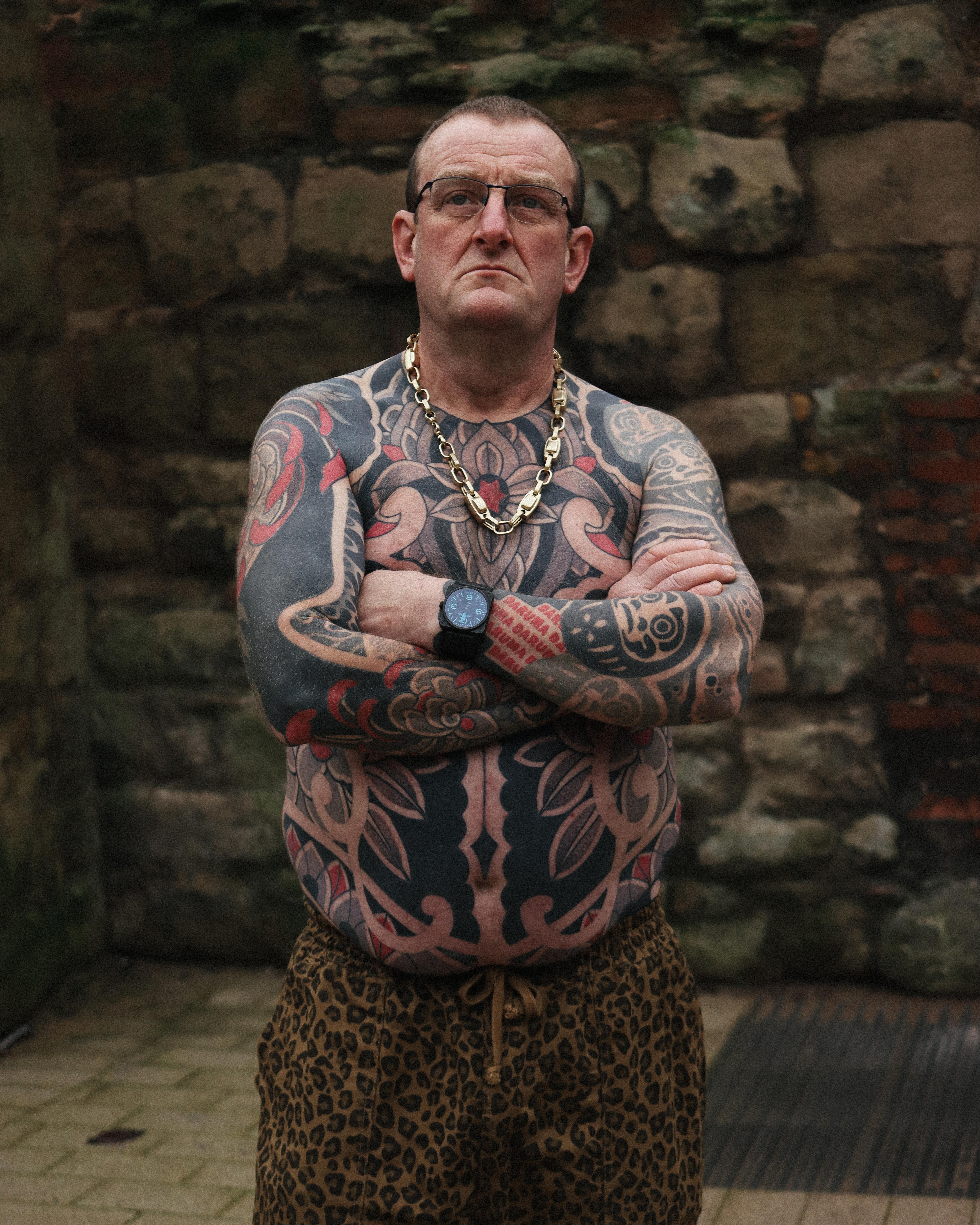 Monolithic blackwork bodysuit across chest and arms, ornate.