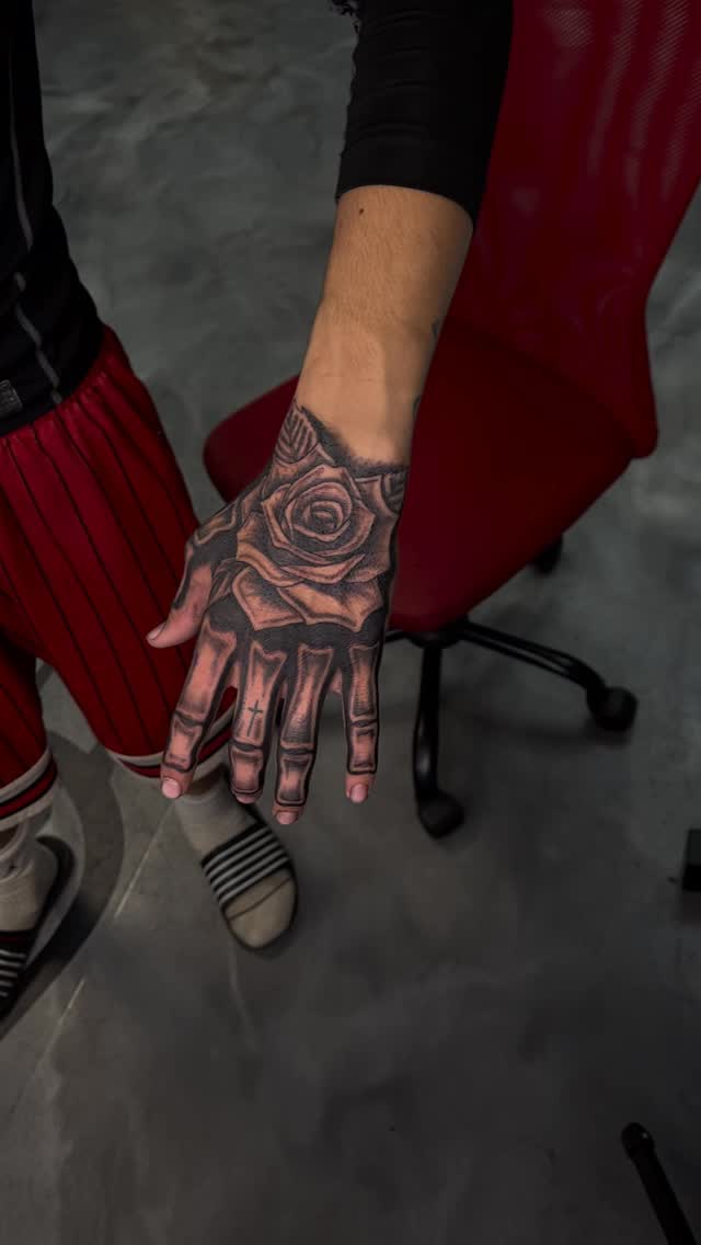 Bold black-and-gray rose on the back of hand