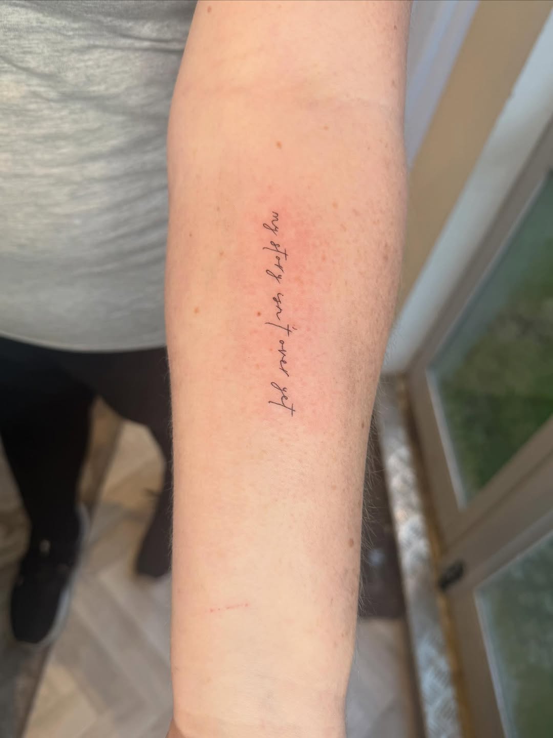 Delicate vertical cursive script along inner forearm