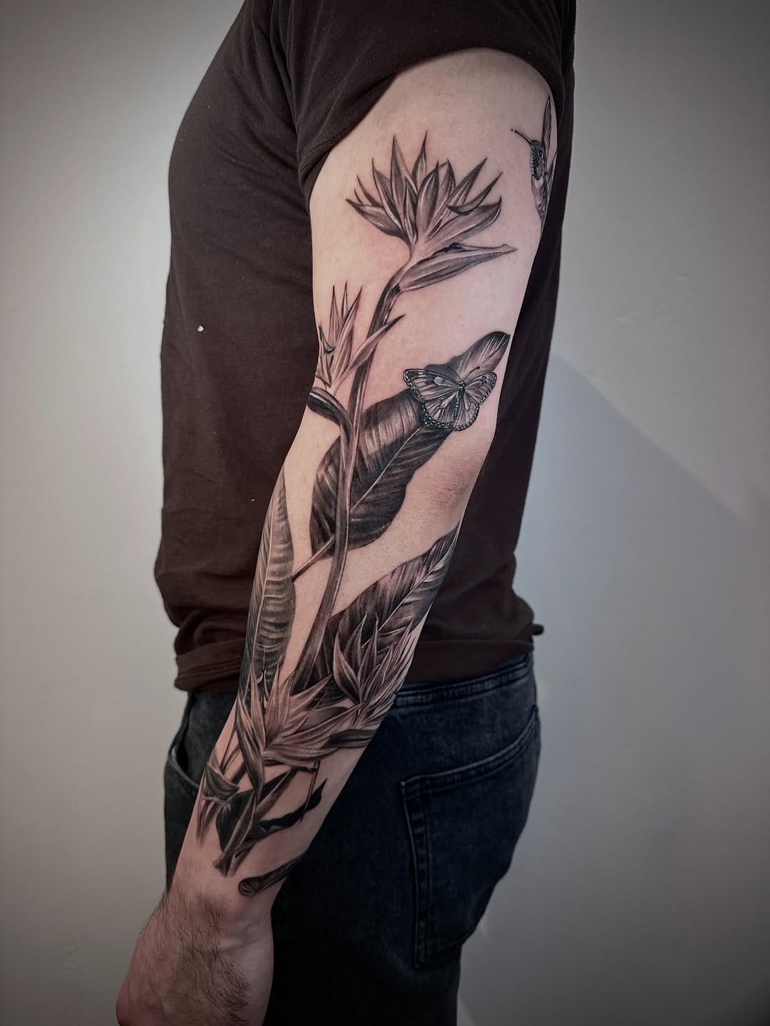 Monochrome bird-of-paradise with butterfly on forearm