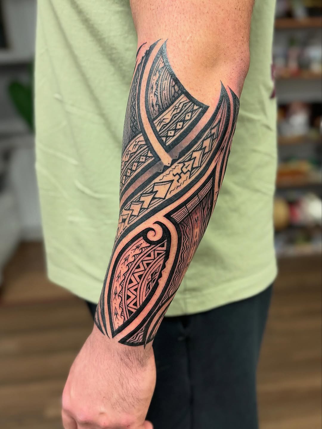 Polynesian-inspired blackwork forearm with intricate geometric tribal patterns