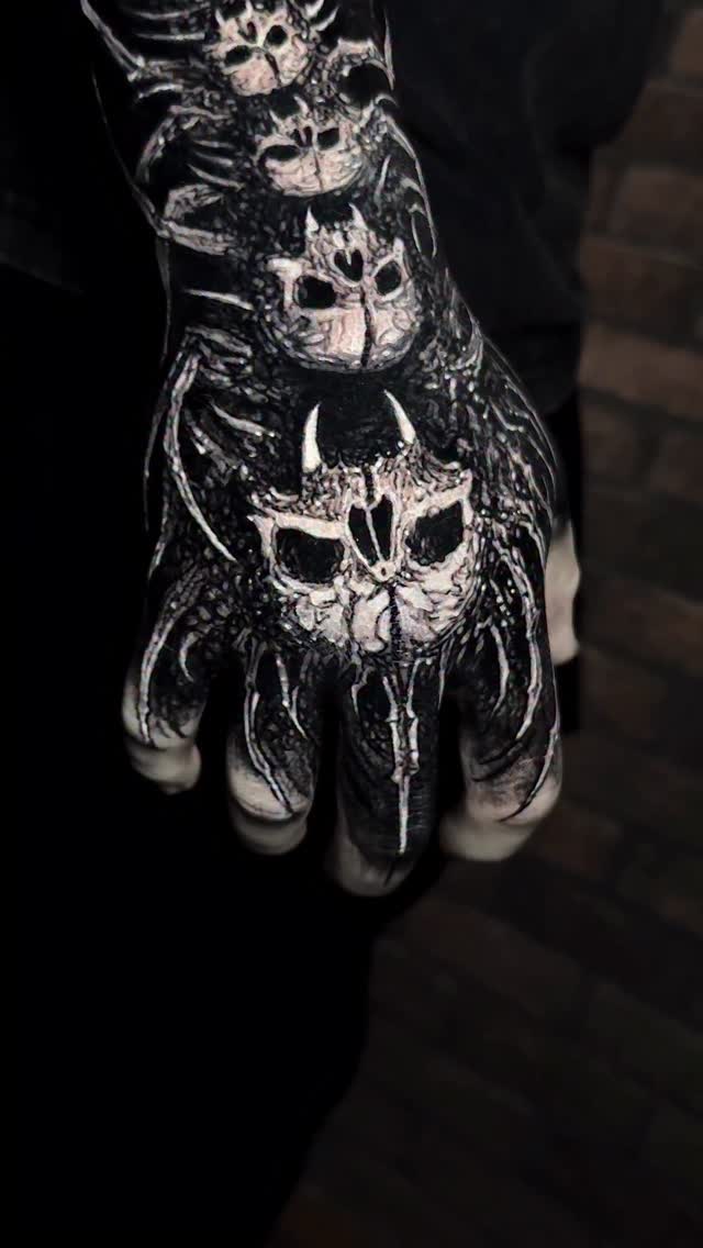 Stacked skulls in high-contrast blackwork on the hand.