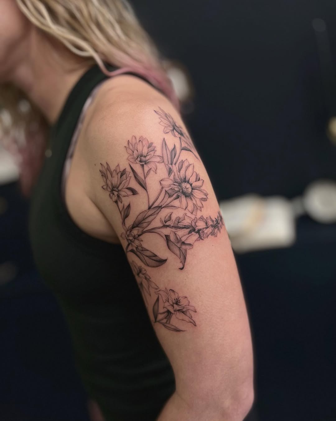 Delicate fine-line floral bouquet wraps the shoulder.