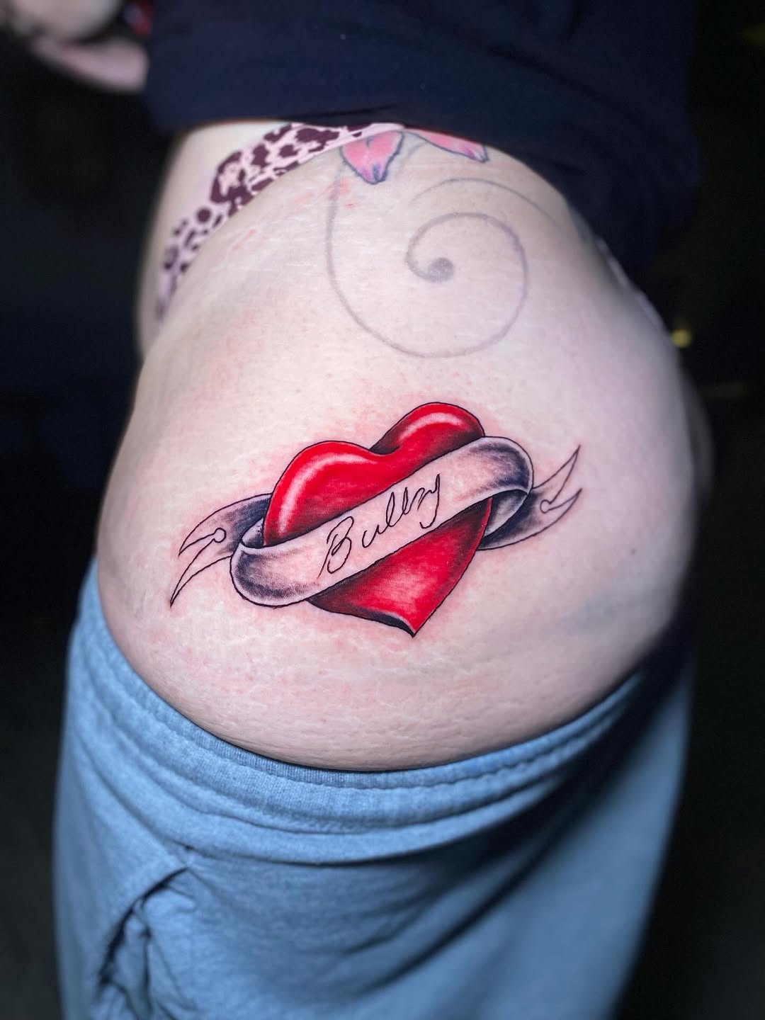 Bold red heart with flowing ribbon, classic traditional tattoo.