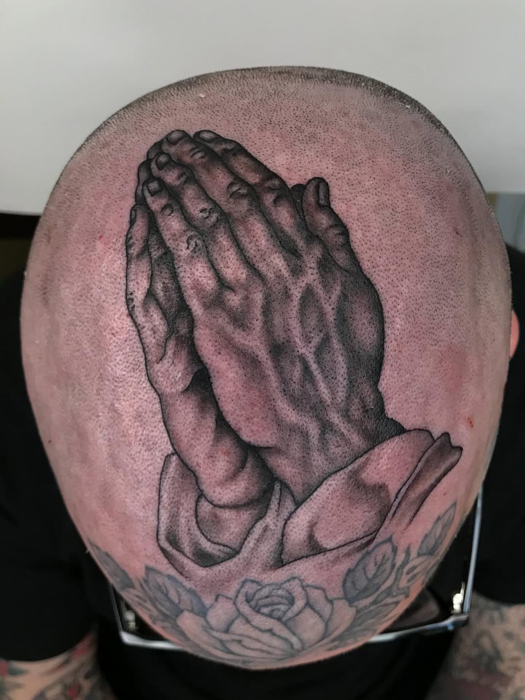 Prayerful hands on shaved scalp with bold shading
