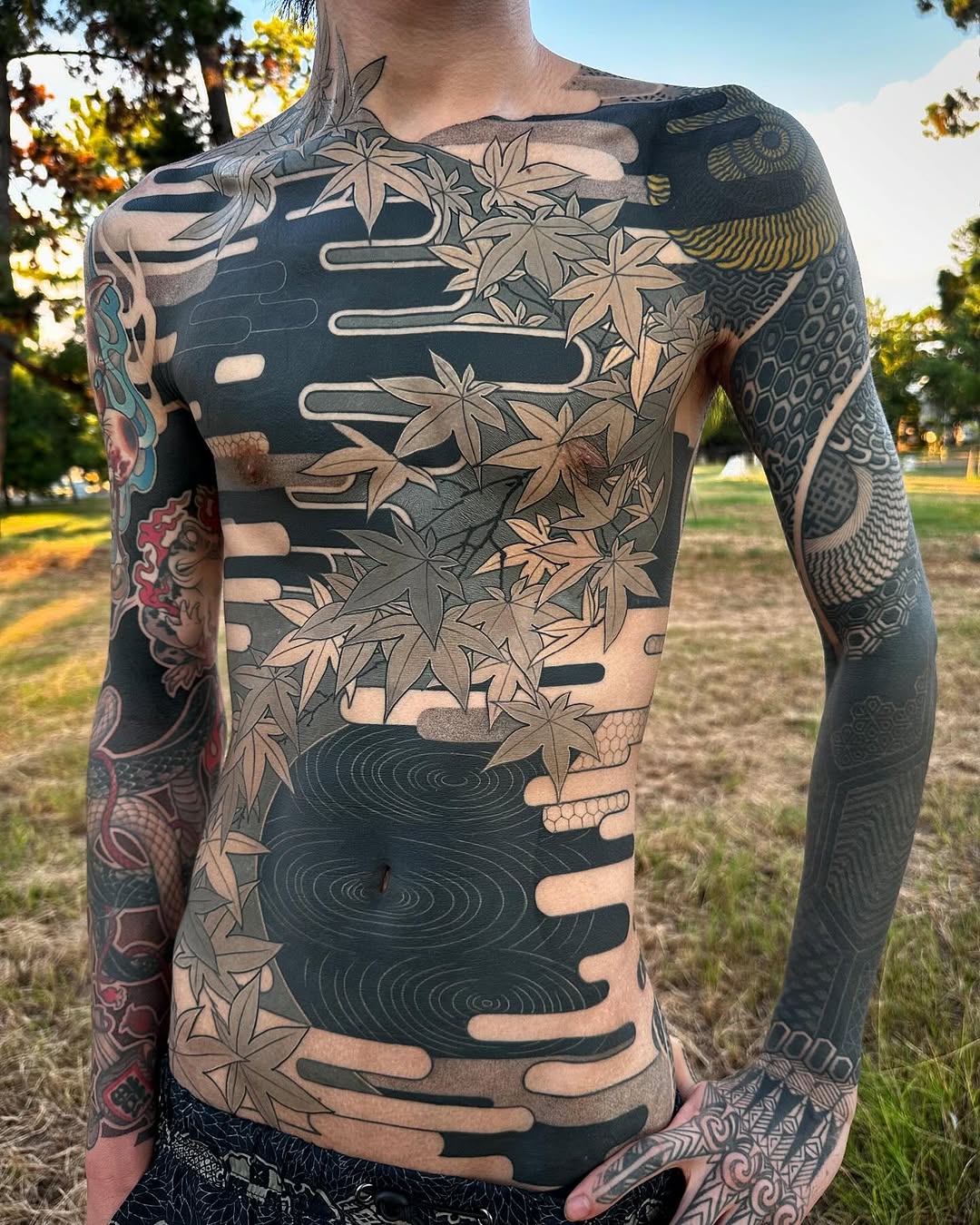 Negative-space maple leaves over bold blackwork with geometric elements