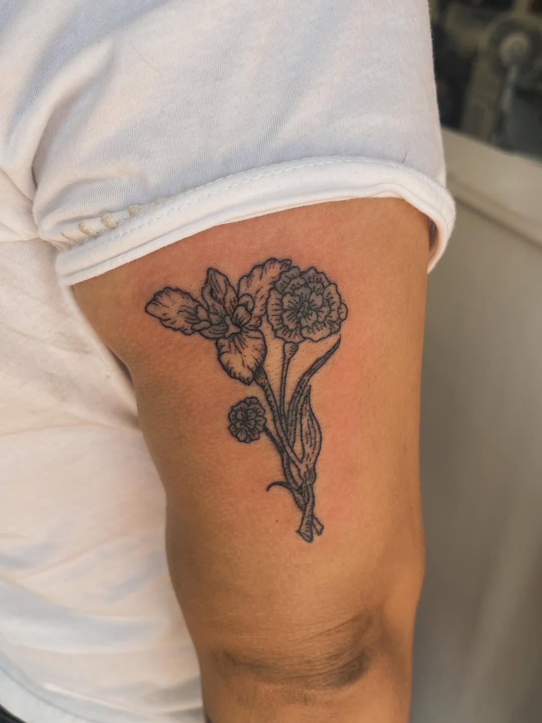 Delicate woodcut-inspired floral linework on upper arm.