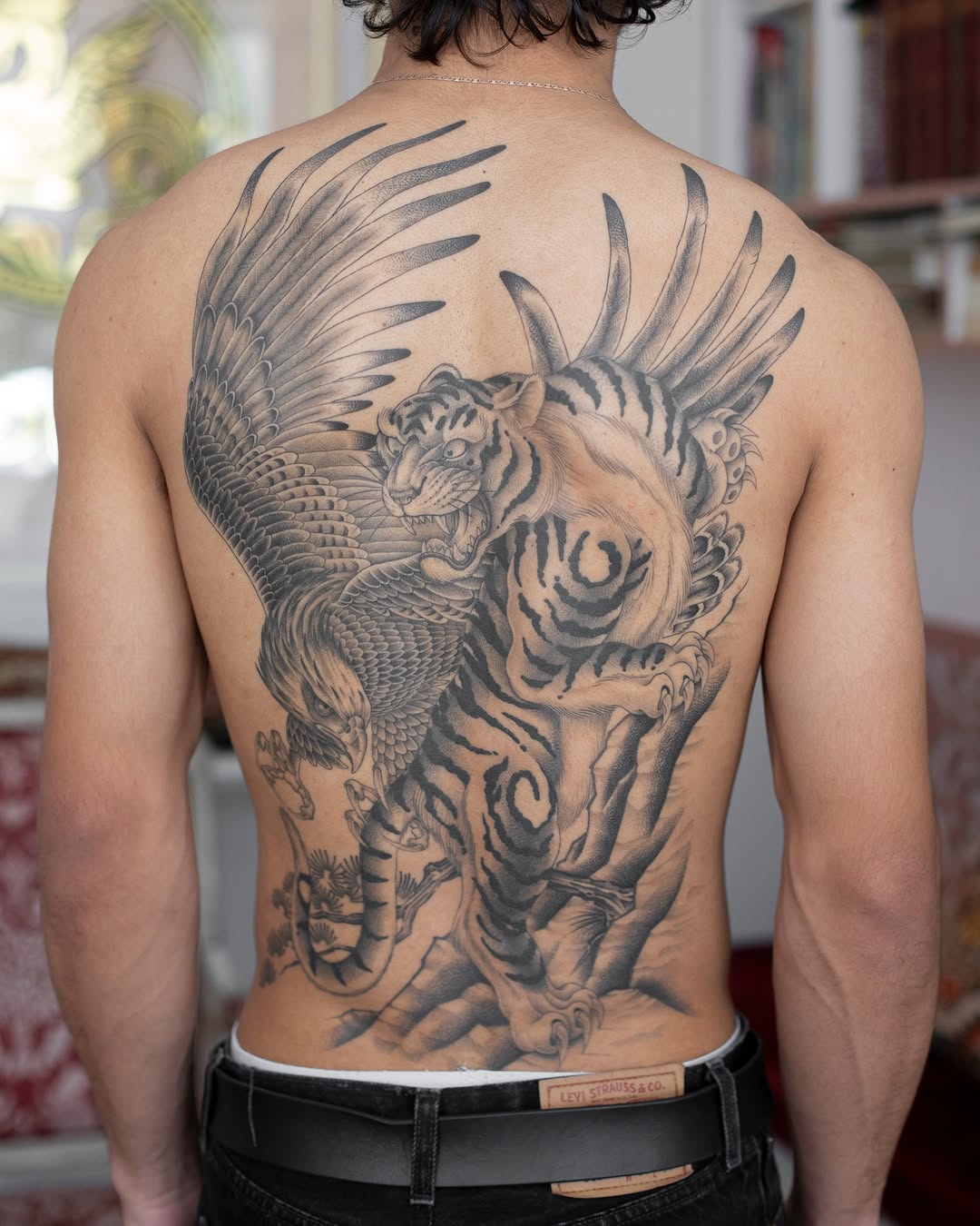 Winged tiger backpiece with bold shading and feathers.