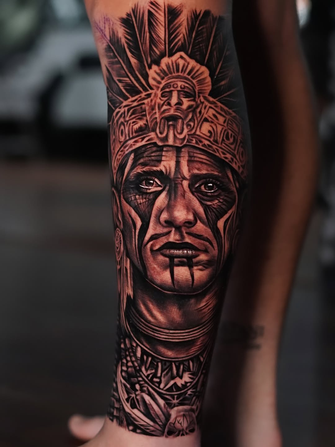 Bold black-and-gray Aztec warrior portrait with feathered headdress