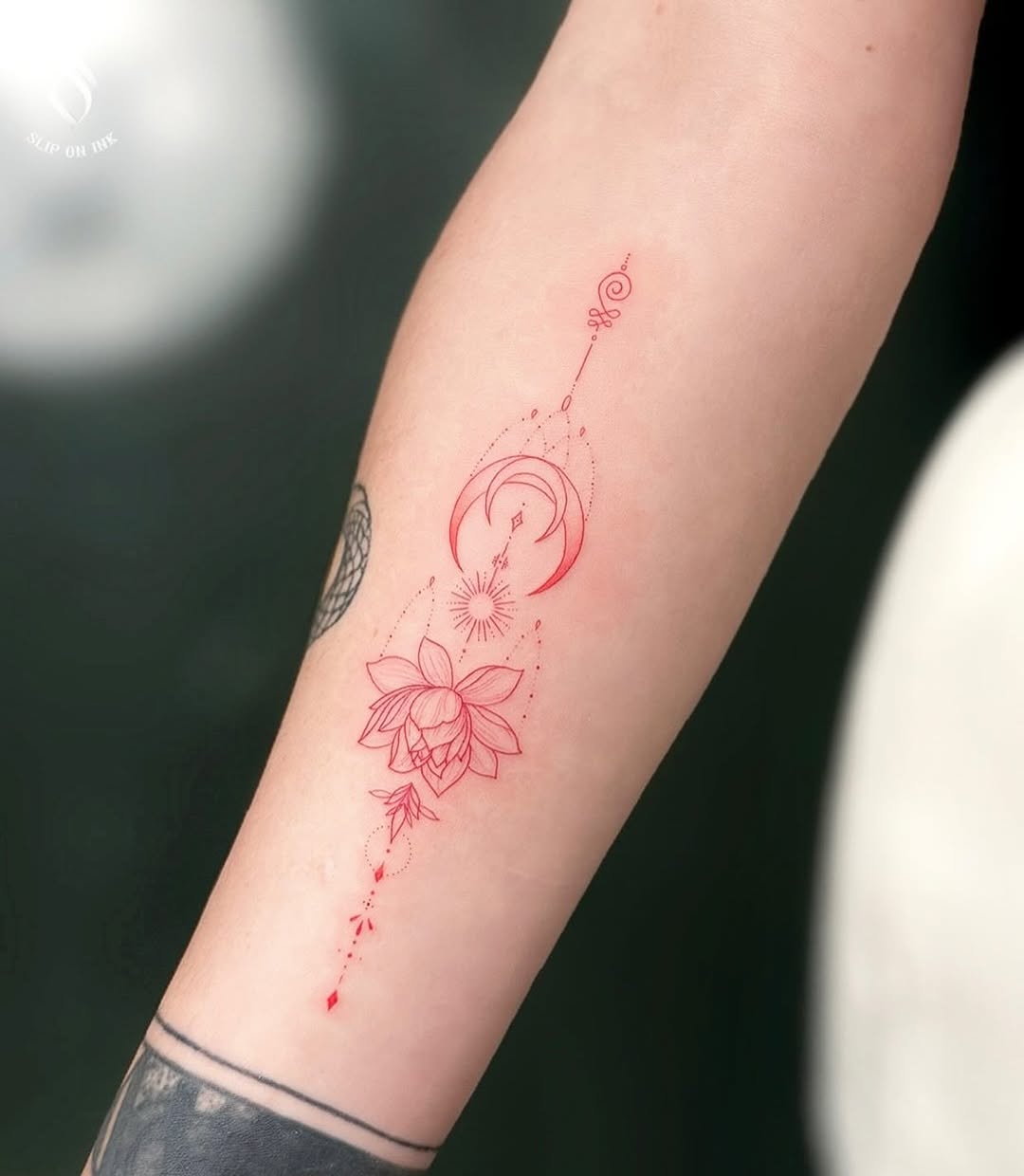 Delicate red fine-line lotus with geometric lunar accents.