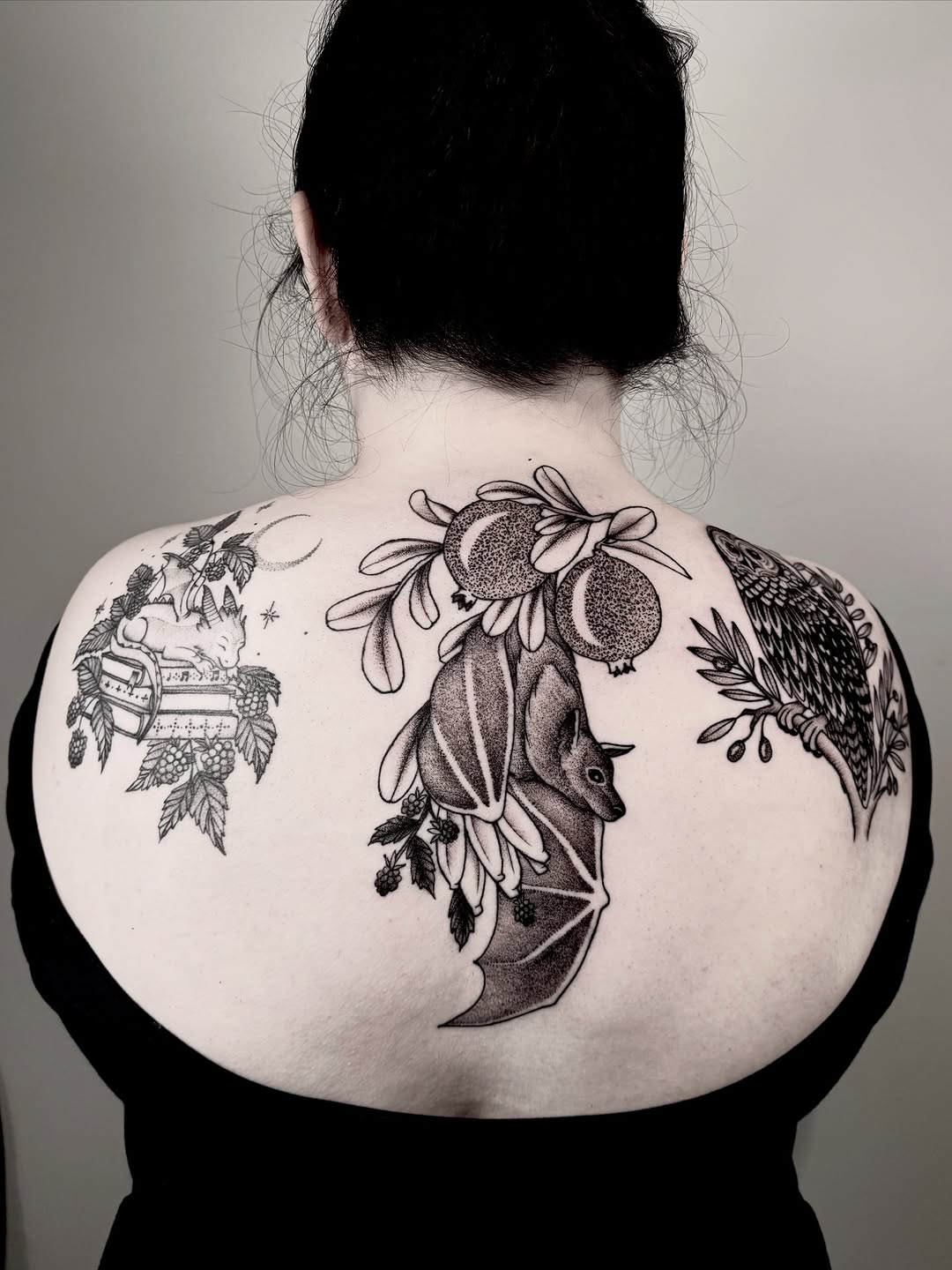 Bold blackwork back piece: floral cluster, fruits, and owl wing