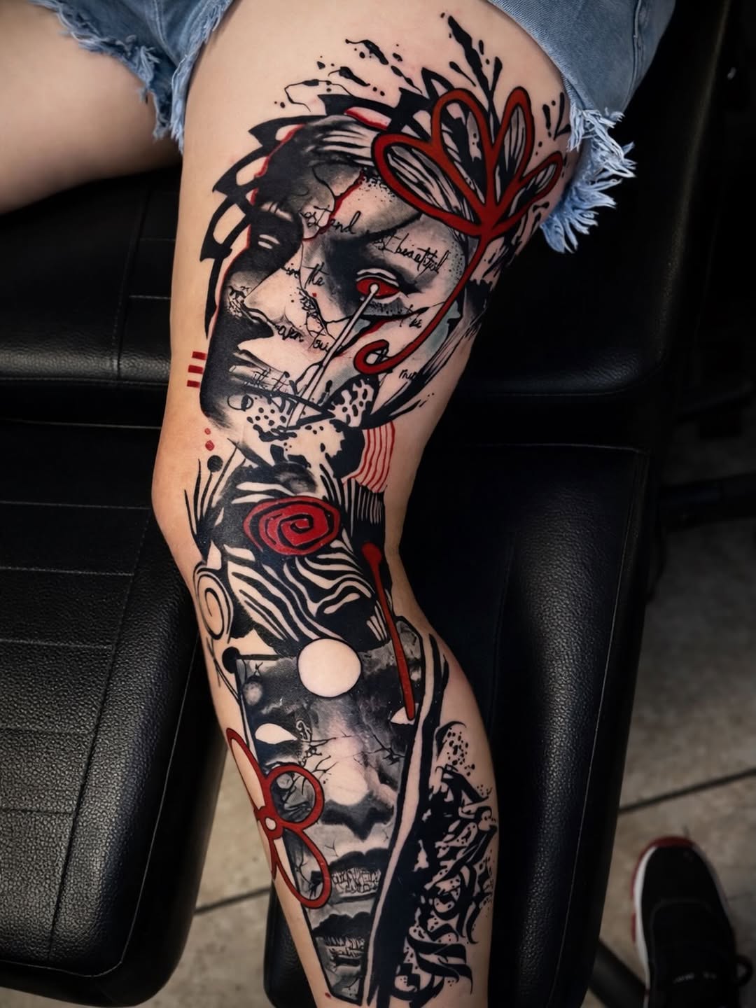 Bold blackwork leg sleeve with red accents and text