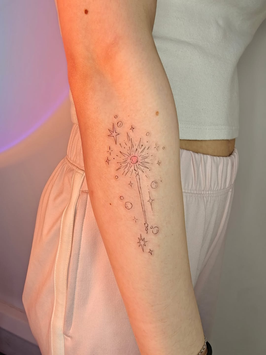 Delicate fine-line wand with starbursts and orbs.