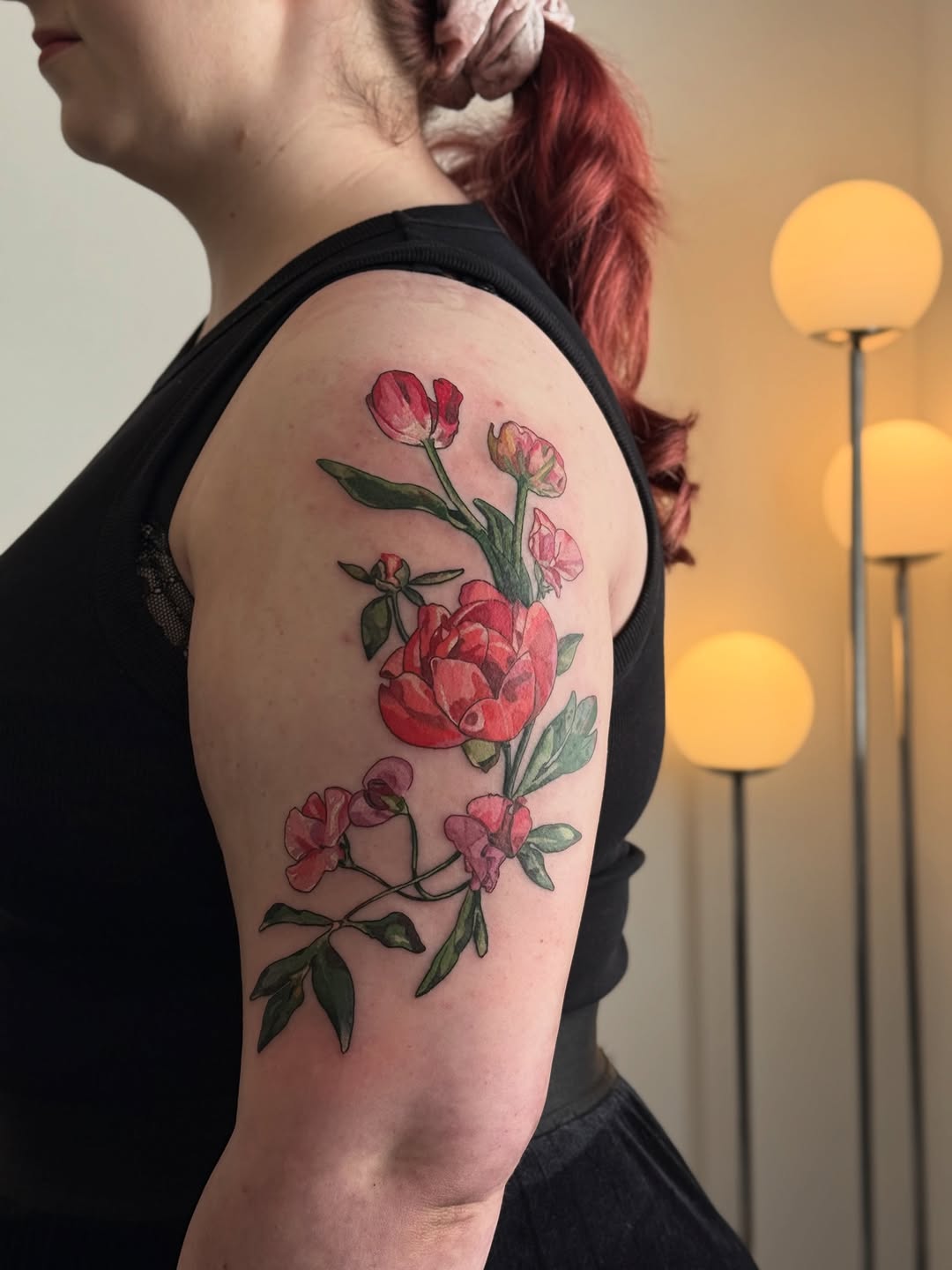 Delicate upper-arm watercolor bouquet of pink blossoms and green leaves