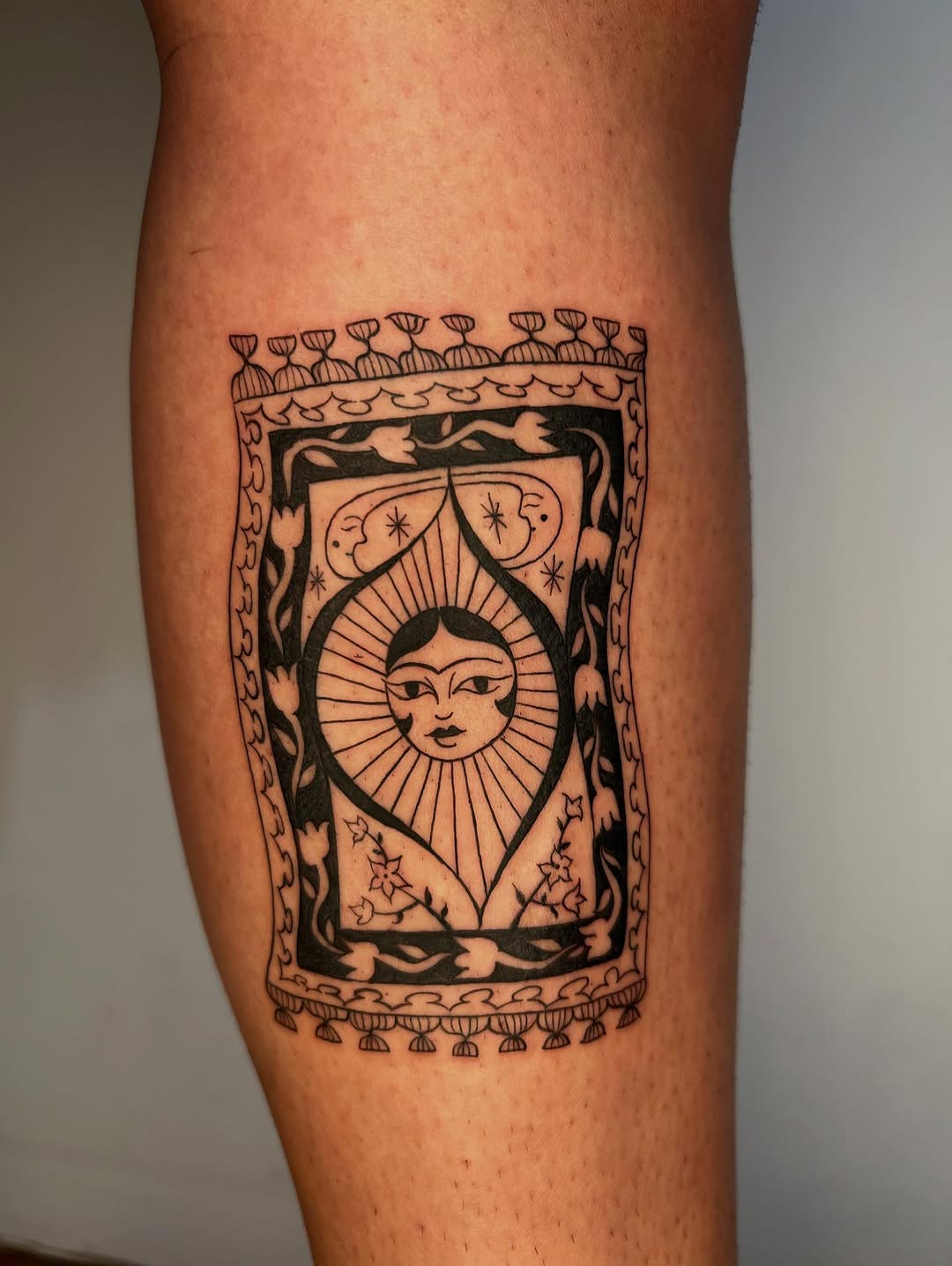 Intricate sun-with-face framed rug motif surrounded by vines