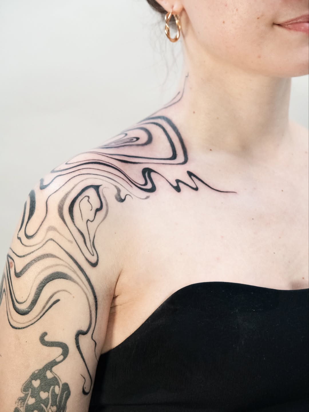 Bold blackwork swirls wrapping shoulder in fluid, abstract motion