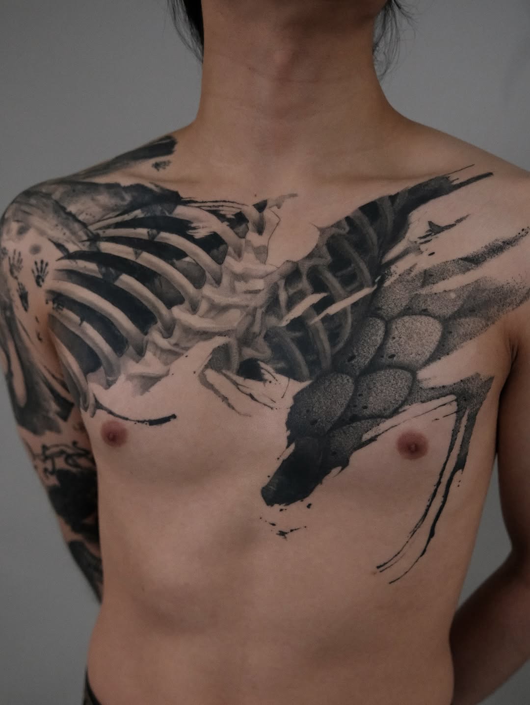 Massive blackwork chest piece blending ribcage and winged scales