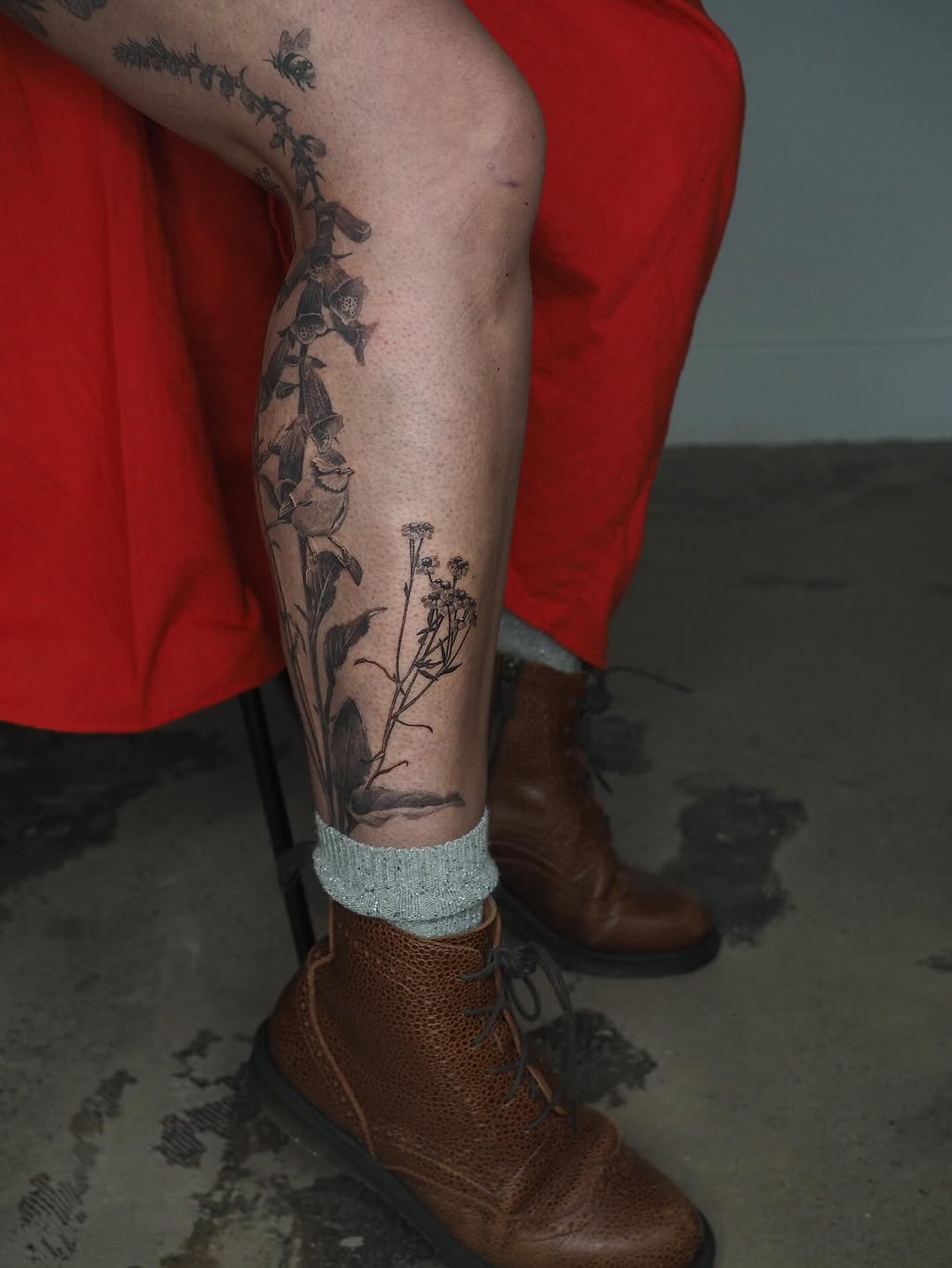 Delicate black botanical vines wrap the leg with blooms