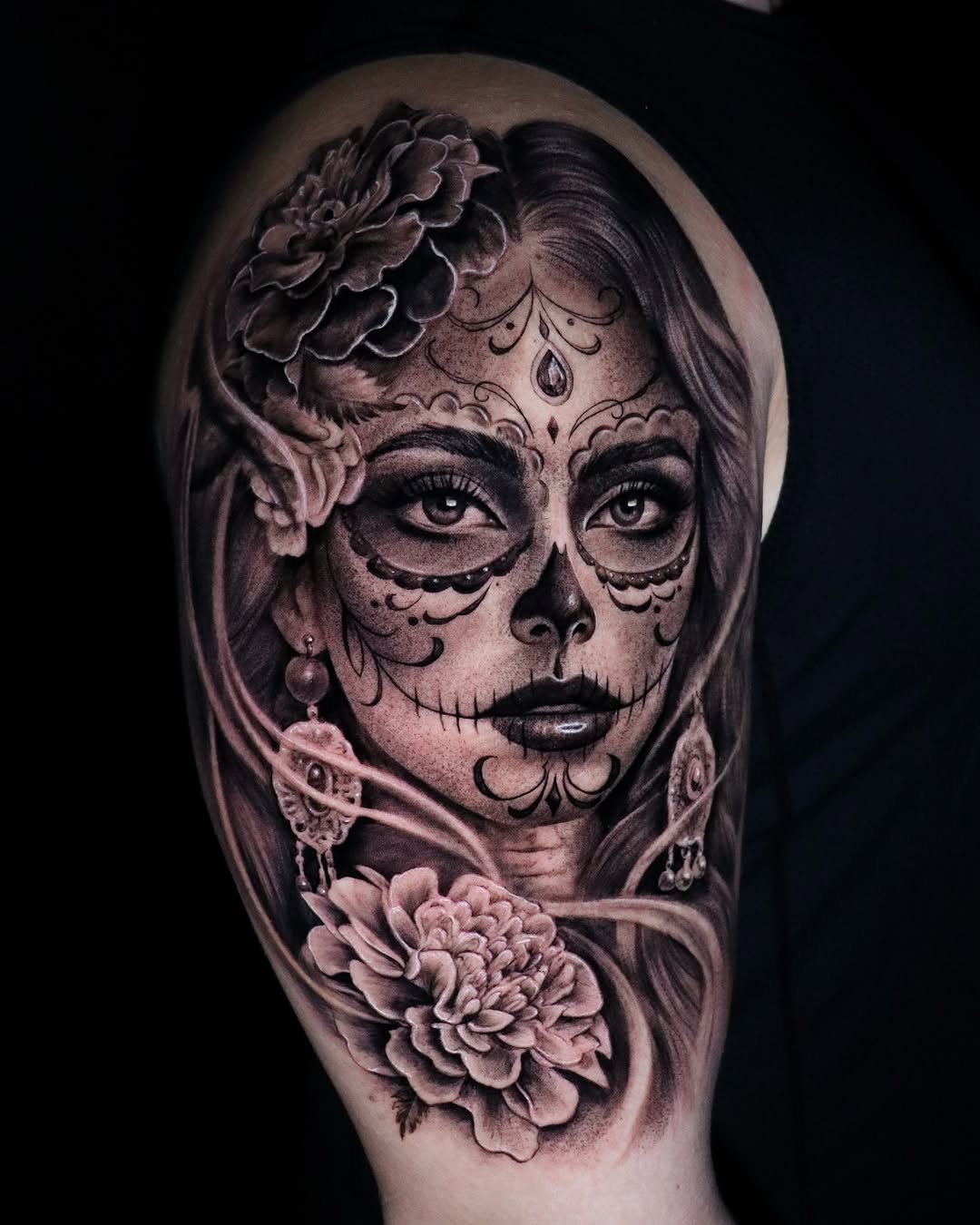 Intricate black-and-gray Dia de los Muertos portrait on the upper arm.