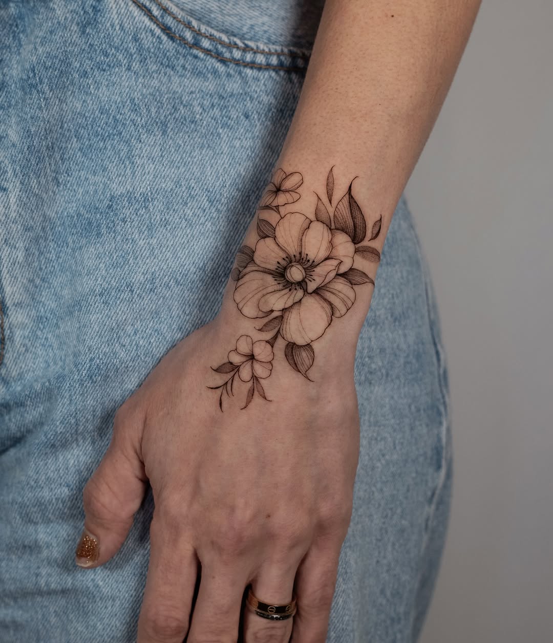 Delicate black-line floral wrist piece featuring a poppy bloom