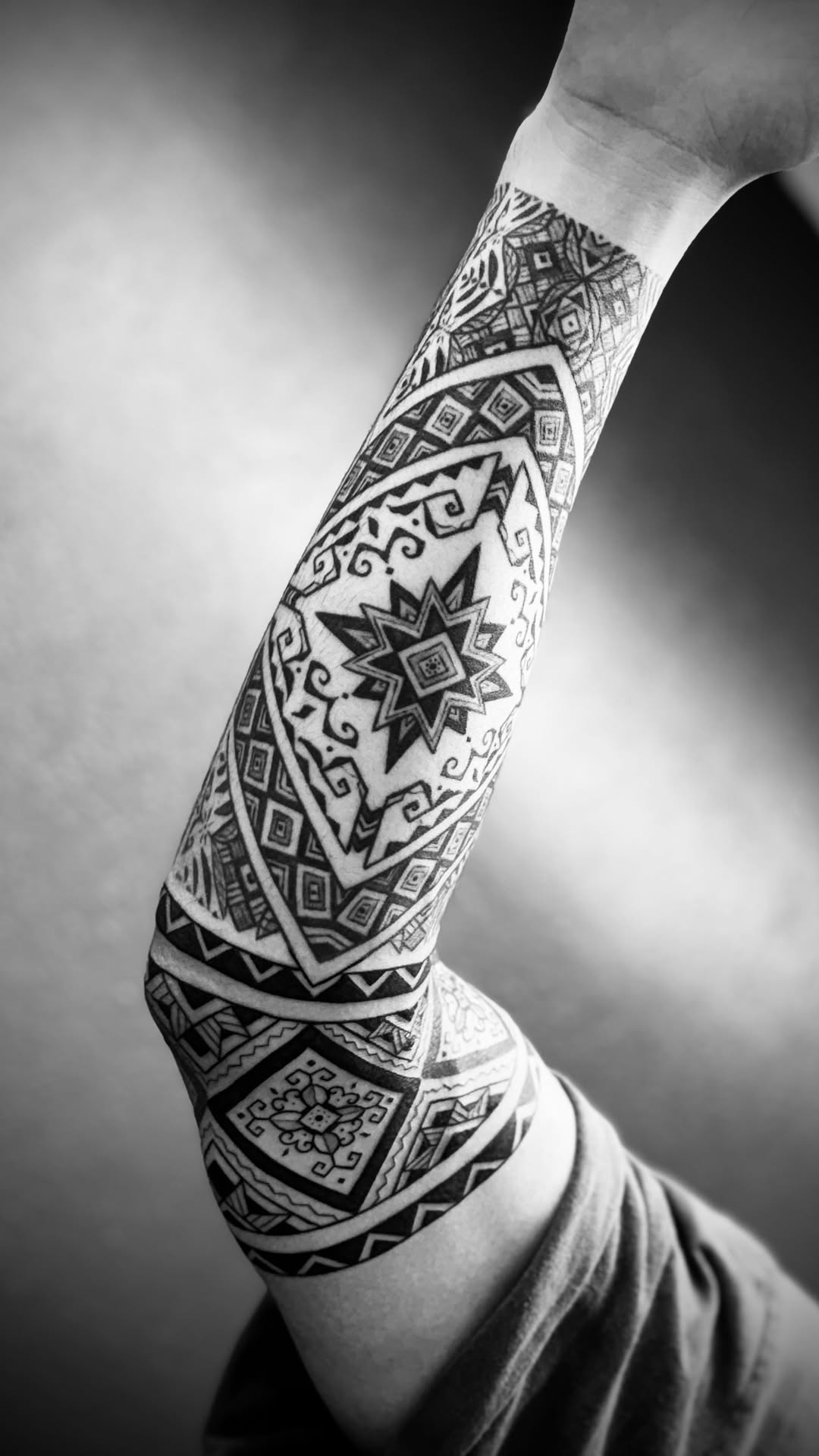 Intricate geometric blackwork forearm sleeve with bold diamonds