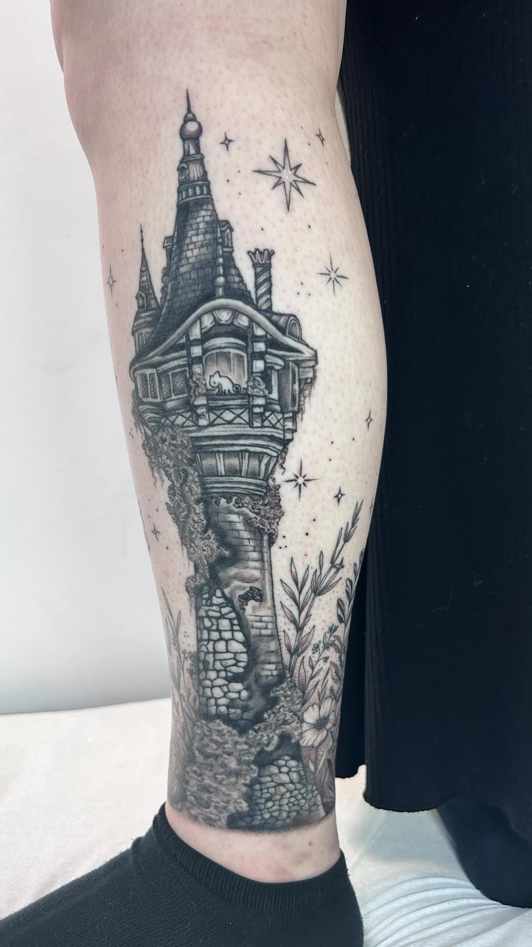 Intricate black-and-gray tower wrapped around calf with flora