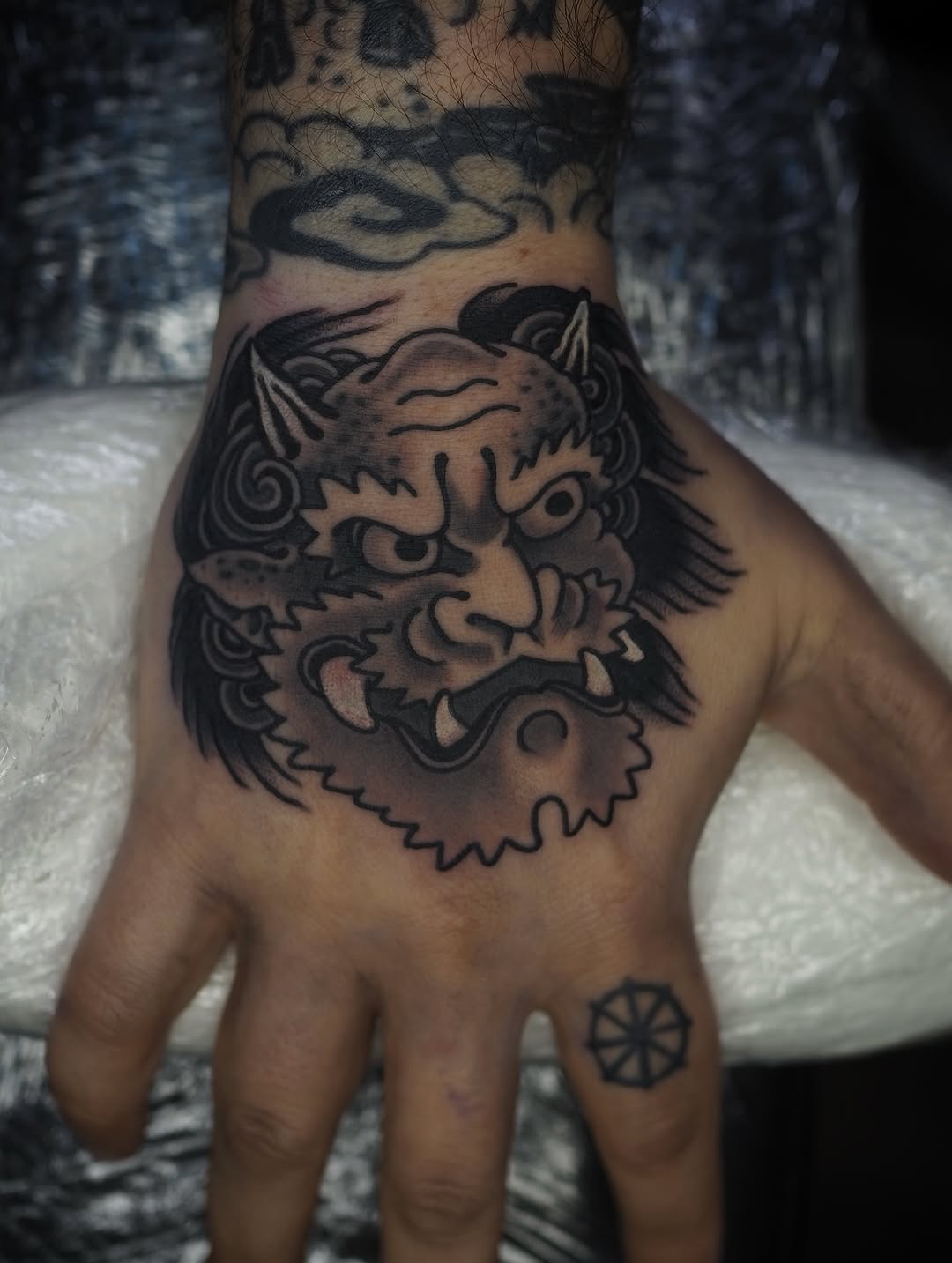 Bold blackwork oni face on back-of-hand with sharp lines