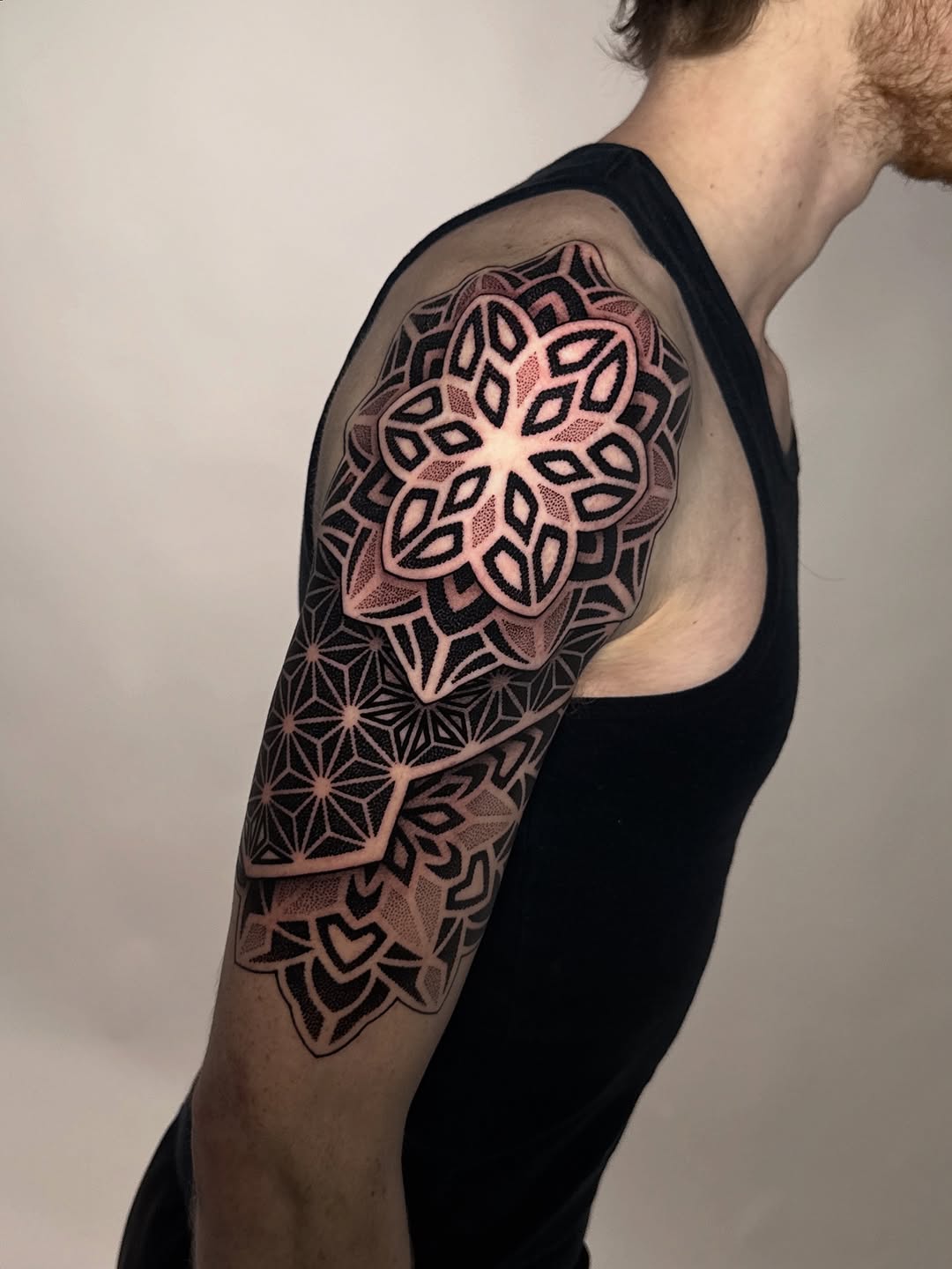 Intricate geometric mandala pattern with dense dotwork shading on upper arm