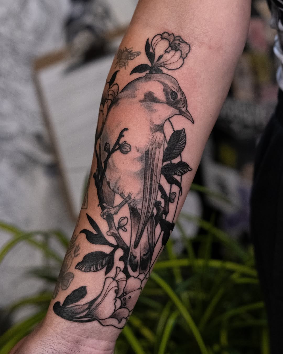 Bold black parrot amid blooming flowers on forearm