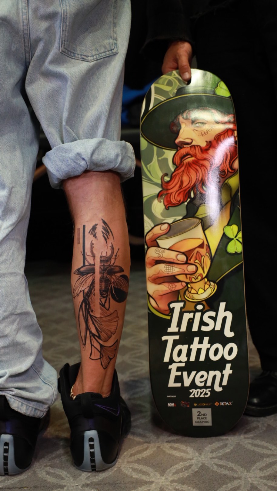 Bold black-line leg tattoo with insect-floral motif