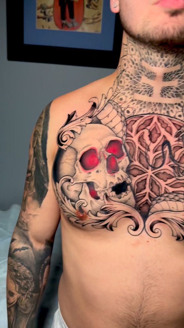 Skull with red sockets amid ornamental scrollwork and mandala.