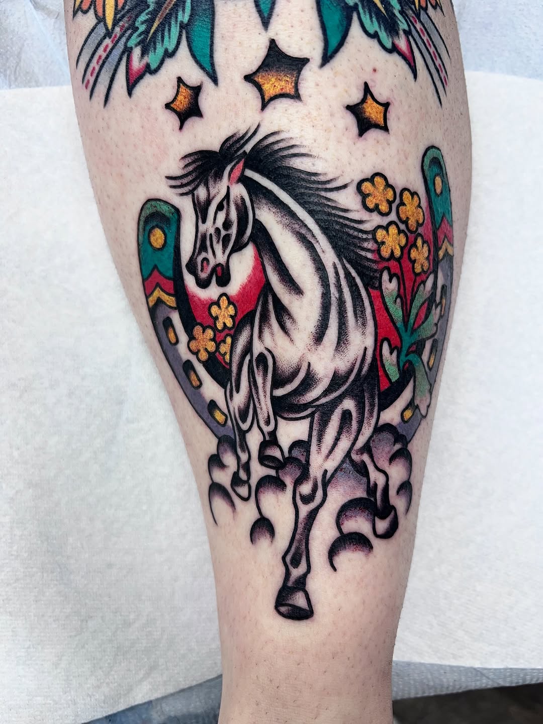 Bold neo-traditional horse rearing amid vibrant floral backdrop