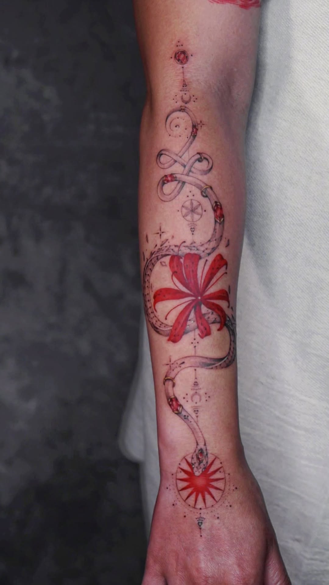 Intricate celestial scrolls loop around a crimson blossom.