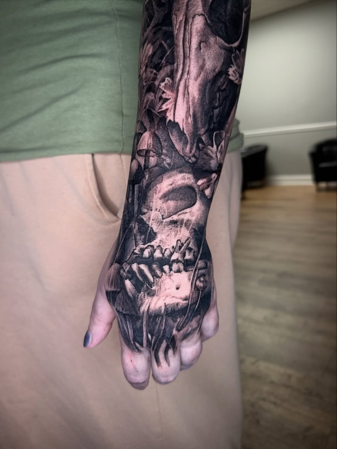 Dark, detailed skull with roses in blackwork forearm tattoo.