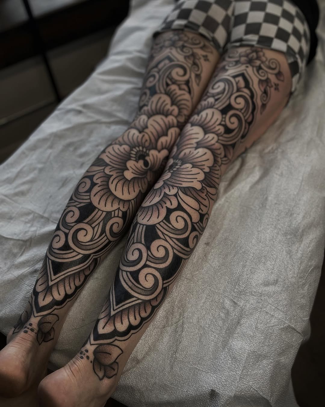 Intricate mirrored blackwork floral leg sleeves with bold swirls